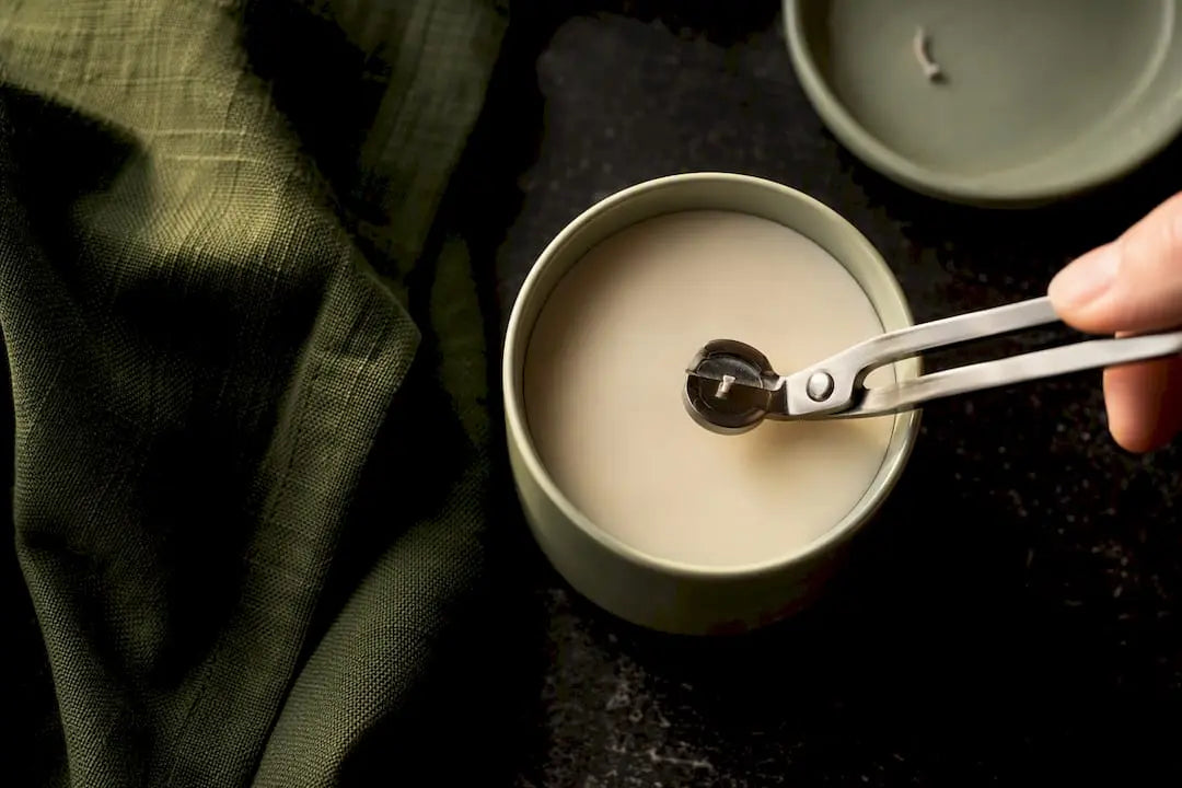 Hand trimming a candle wick close-up